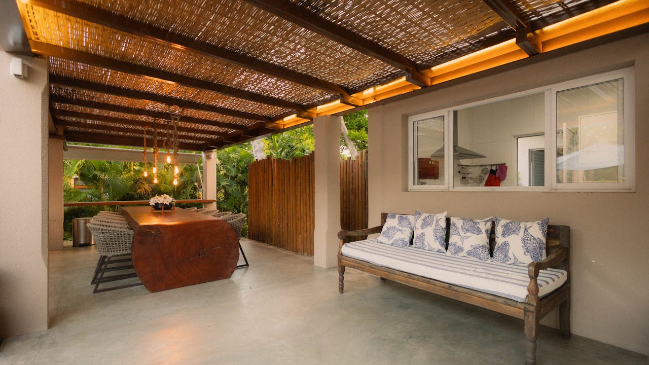 Stylish outdoor patio featuring modern wooden dining table, seating area, and ambient lighting.